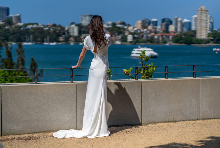 a woman in a white dress looking at a body of water